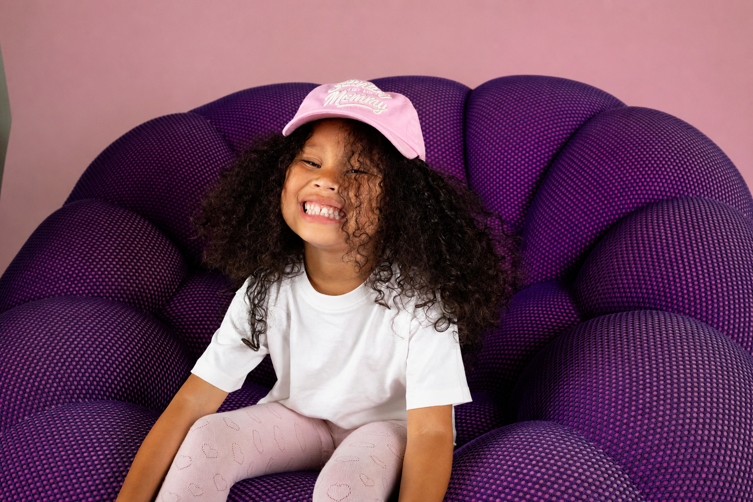 A child smiling in their pink hat