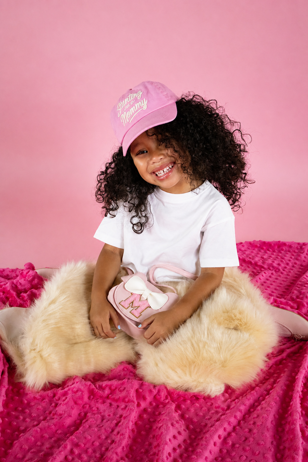 A child smiling in a pink Stunting Like My Mommy hat