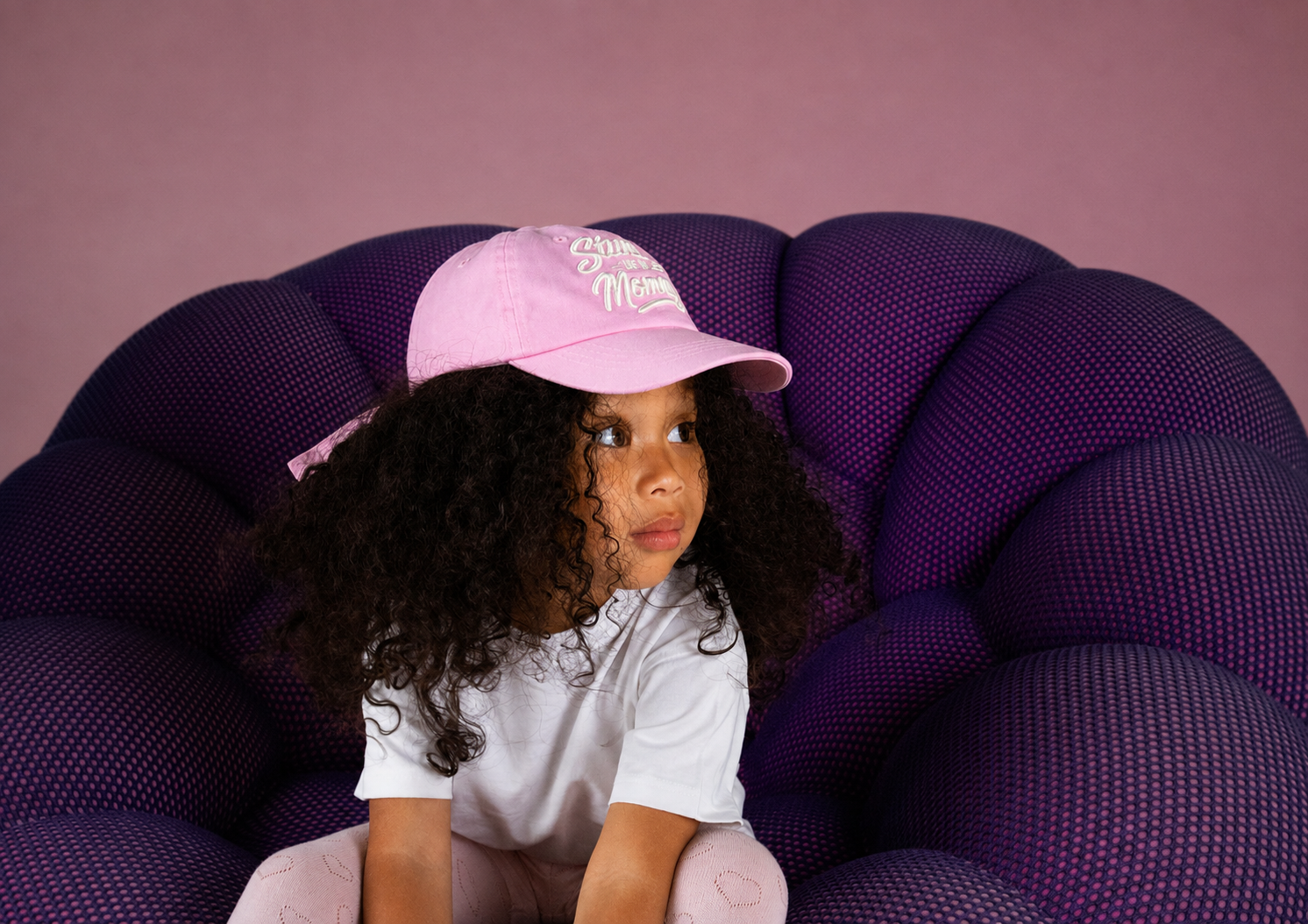 A child relaxing in their pink Stunting Like My Mommy hat